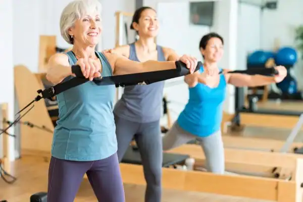 Toning Arms After 60: Empowering Womens Fitness Through Effective Weight Training 2 older woman doing weight training Cambridgeshire and resistance in the gym to tone upper arms