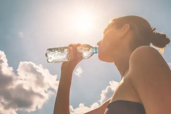 Hydration: The Secret Ingredient for a Toned Stomach and Enhanced Fitness 3 Image of woman drinking water to hydrate Cambridgeshire after run.