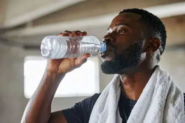 Image of man drinking water to improve hydration Cambridgeshire after work out.